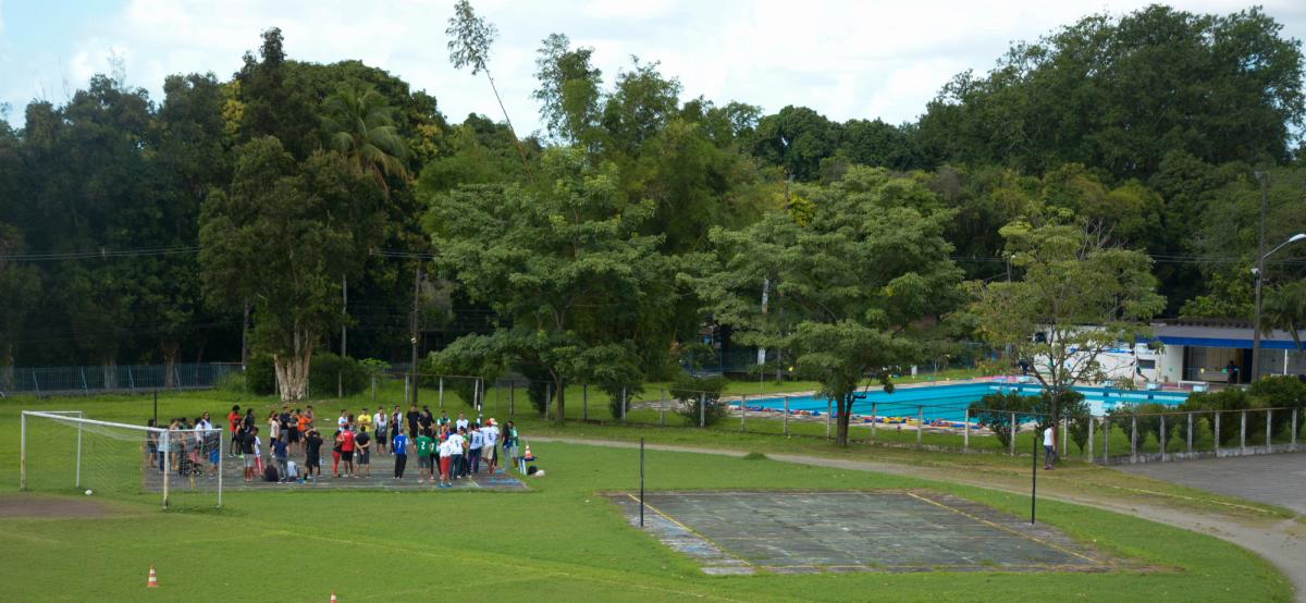 Imagem da área esportiva que fica em frente ao prédio central da ufrpe, mostrado uma quadra onde estão os estudantes, a piscina e o campo de futebol