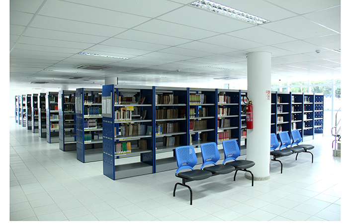 imagem do interior da biblioteca, com estantes de livros, cadeiras e mesas