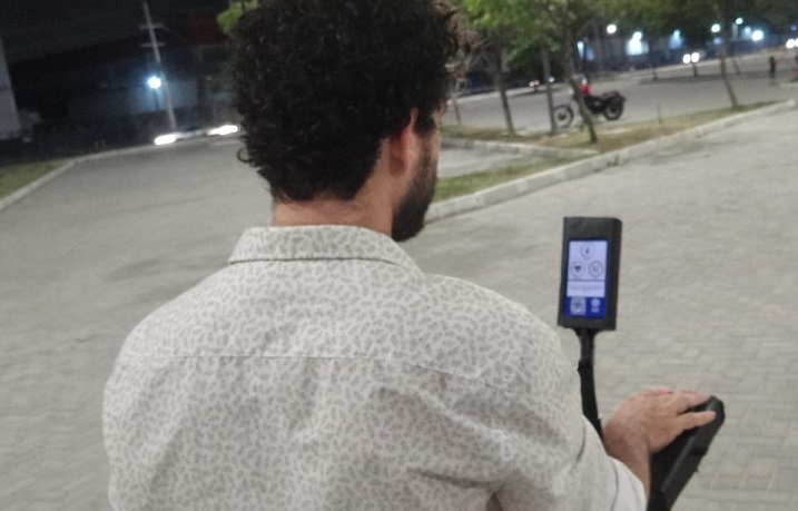 estudante com dispositivo em rua, de costas