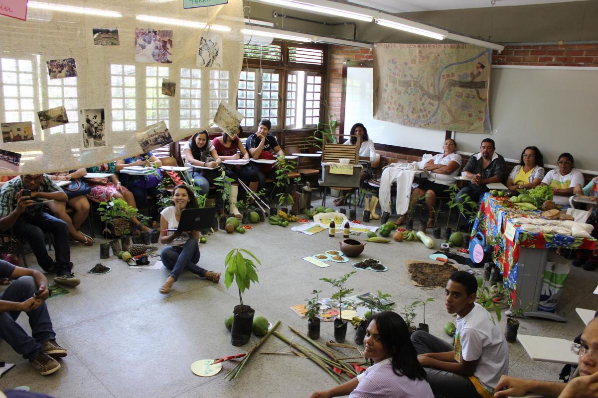 jovens rurais, sentados em circulo numa sala de aula, com plantas e elementos de artesanato